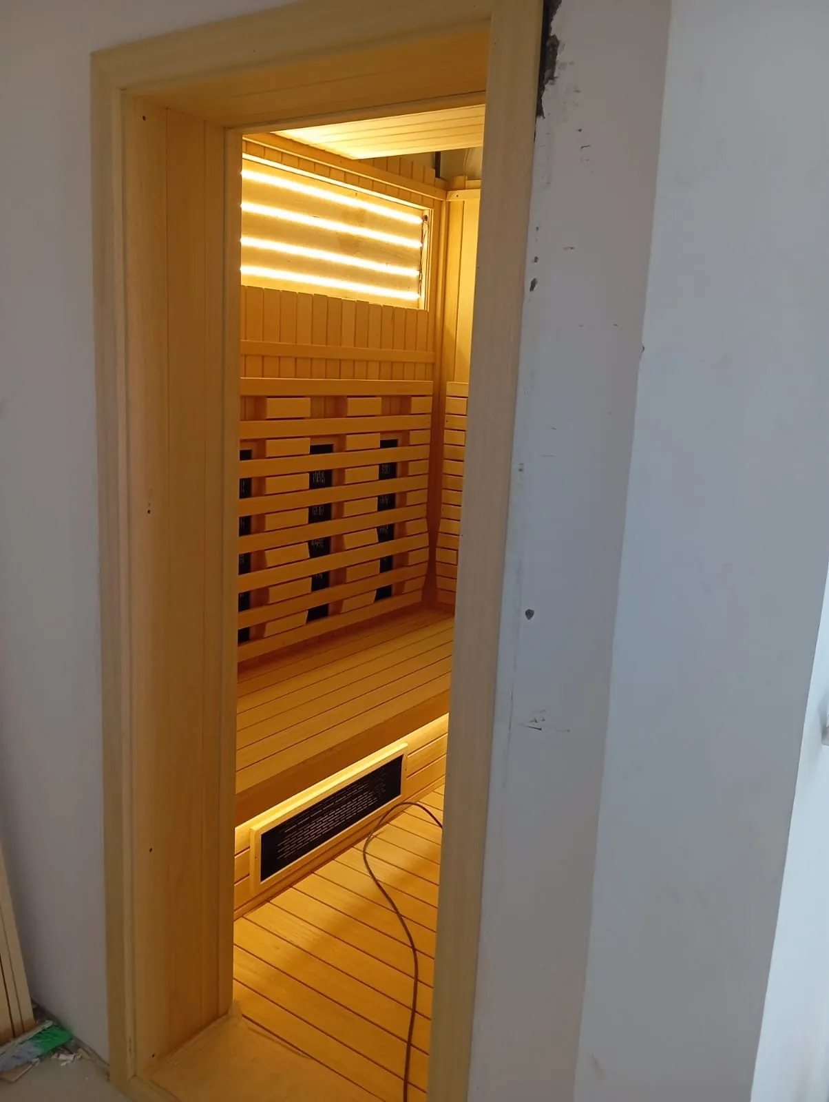 View through the doorway into a lit infrared sauna cabin