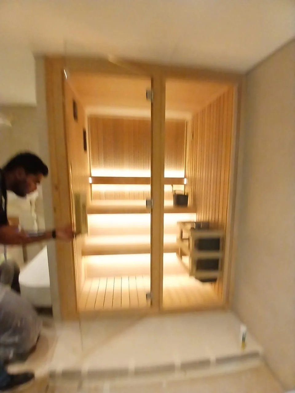 Technician fitting a full height glass door to a new sauna cabin