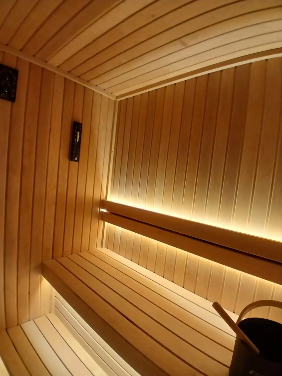 Backlit bench and bucket inside a finished hemlock sauna cabin